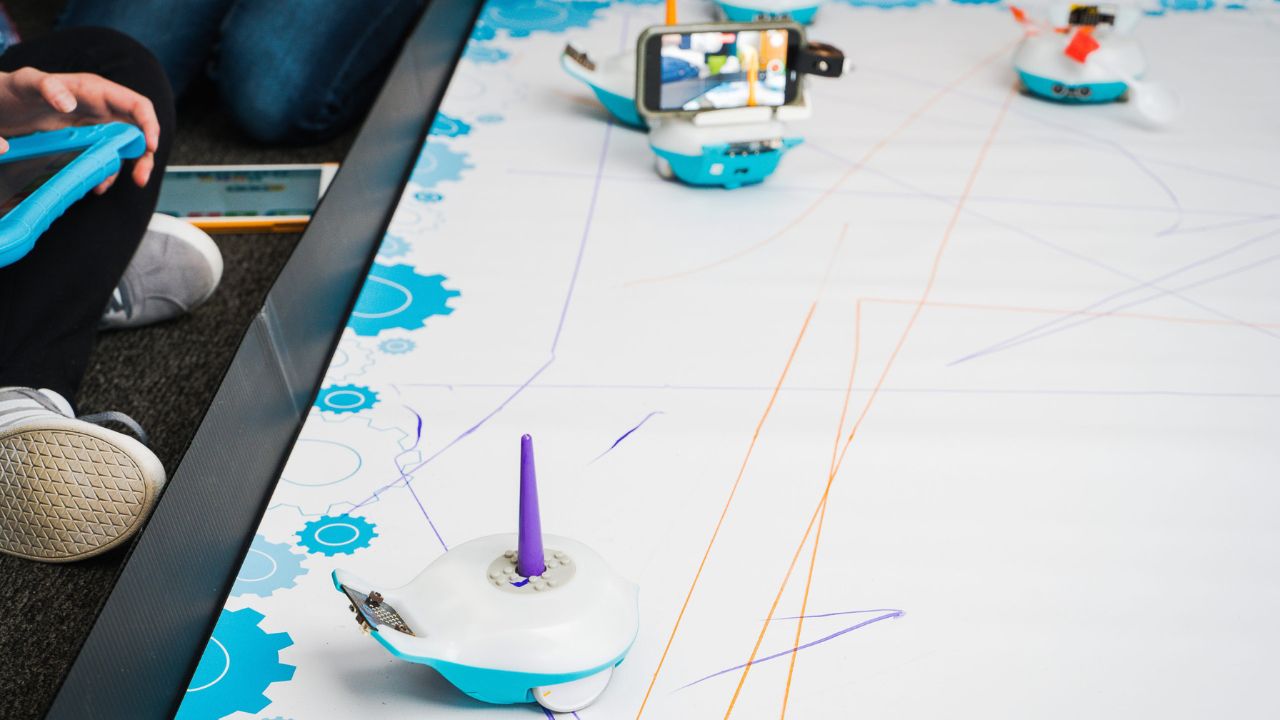 A student sends the Finch Robot 2.0 across a drawing mat, watching lines of code become lines on paper.