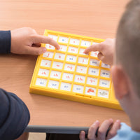 Child pressing a tile on the Jolly Phonics Chatter Board to hear a phonics sound.