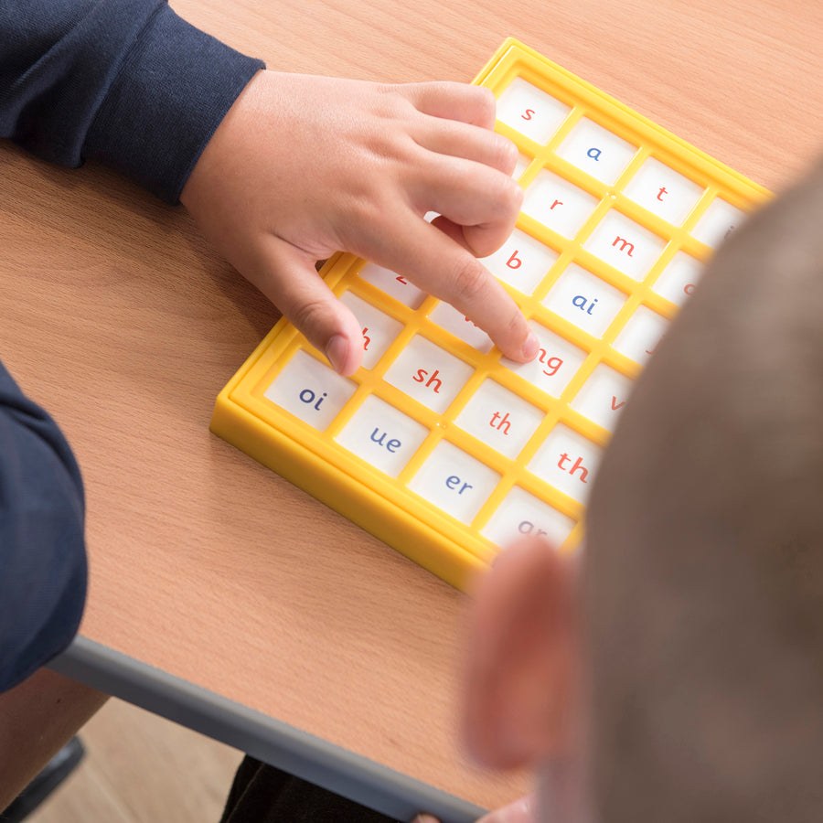 Child pressing a tile on the Jolly Phonics Chatter Board to hear a phonics sound.