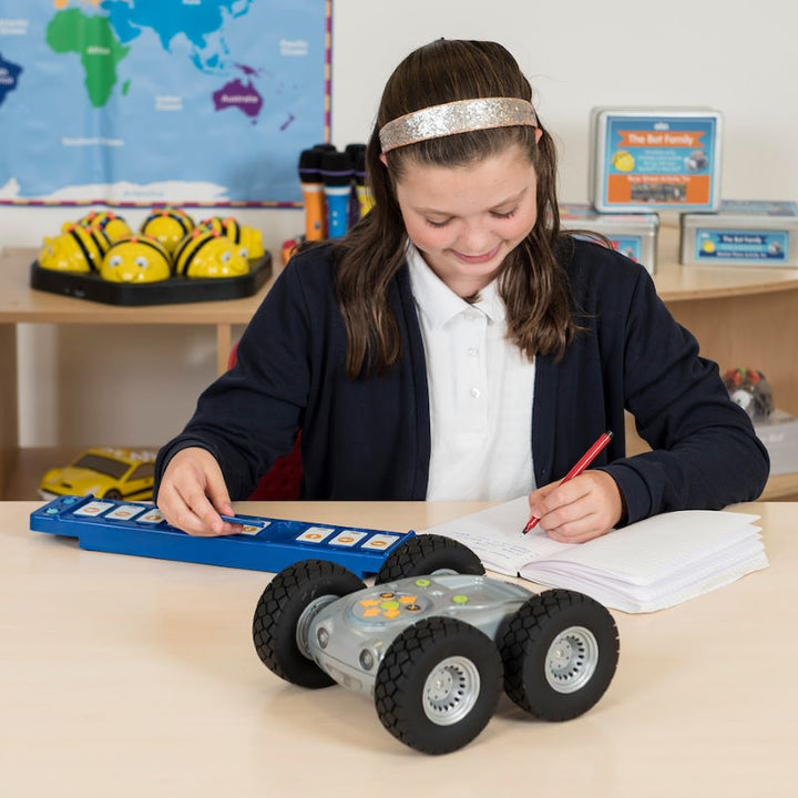 Girl in a classroom setting with a robot on her desk