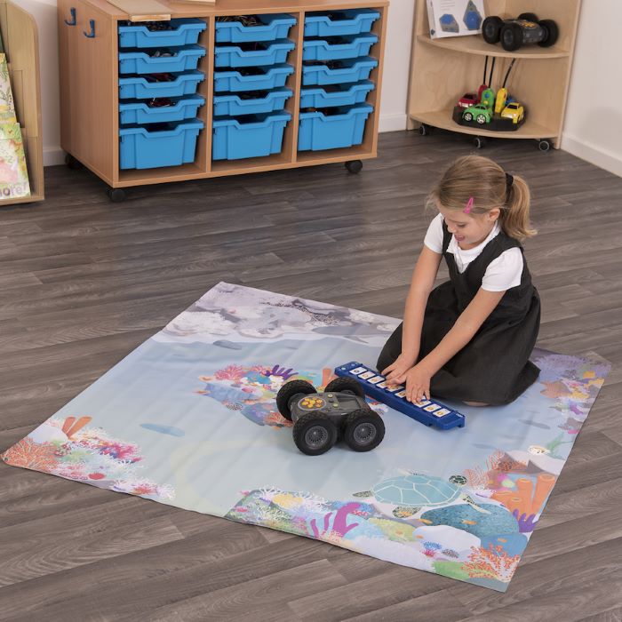 Child playing with rugged robot on a colorful mat in a classroom setting